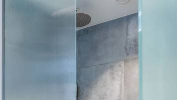 A modern bathroom with a glass shower enclosure, tiled walls, and a visible showerhead.