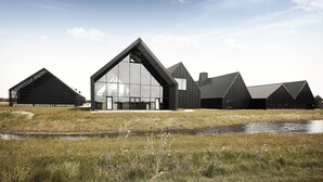 A modern building with large glass windows and a prominent triangular roof structure. - Hotel Skjern (Skjern)
