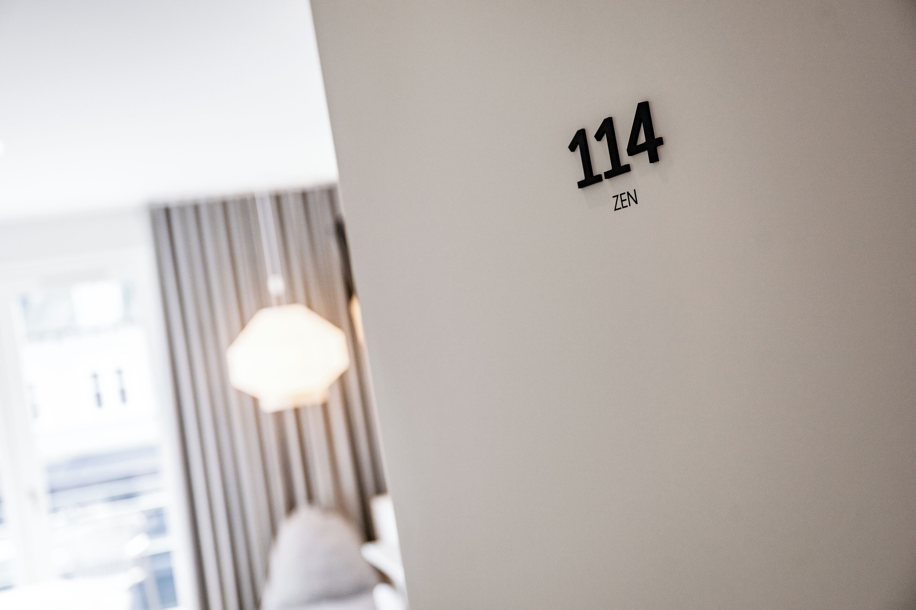 Un mur portant le numéro « 114 » et le mot « ZEN », indiquant une pièce ou un lieu.