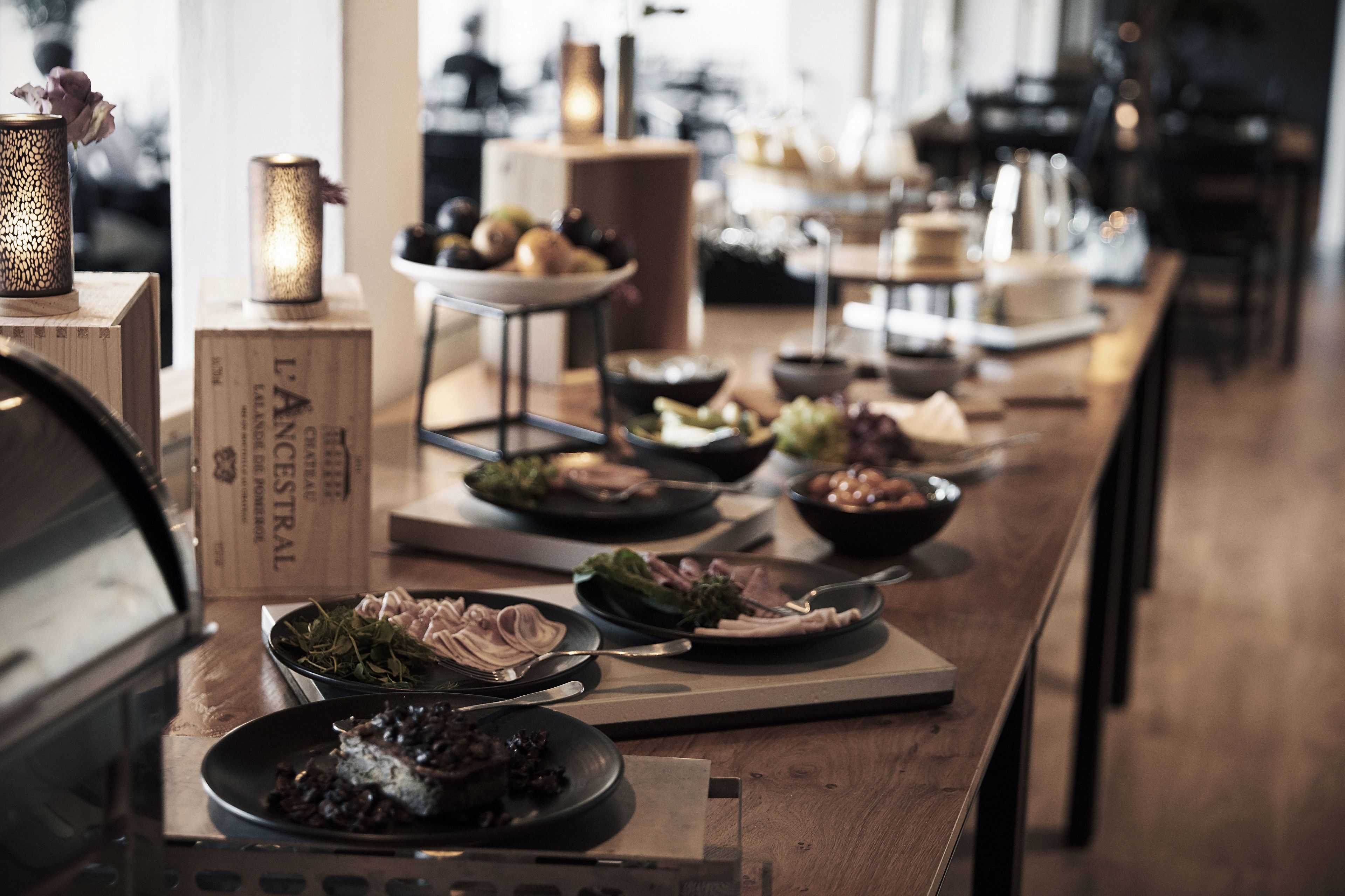 A long wooden table with various dishes and a candle holder.