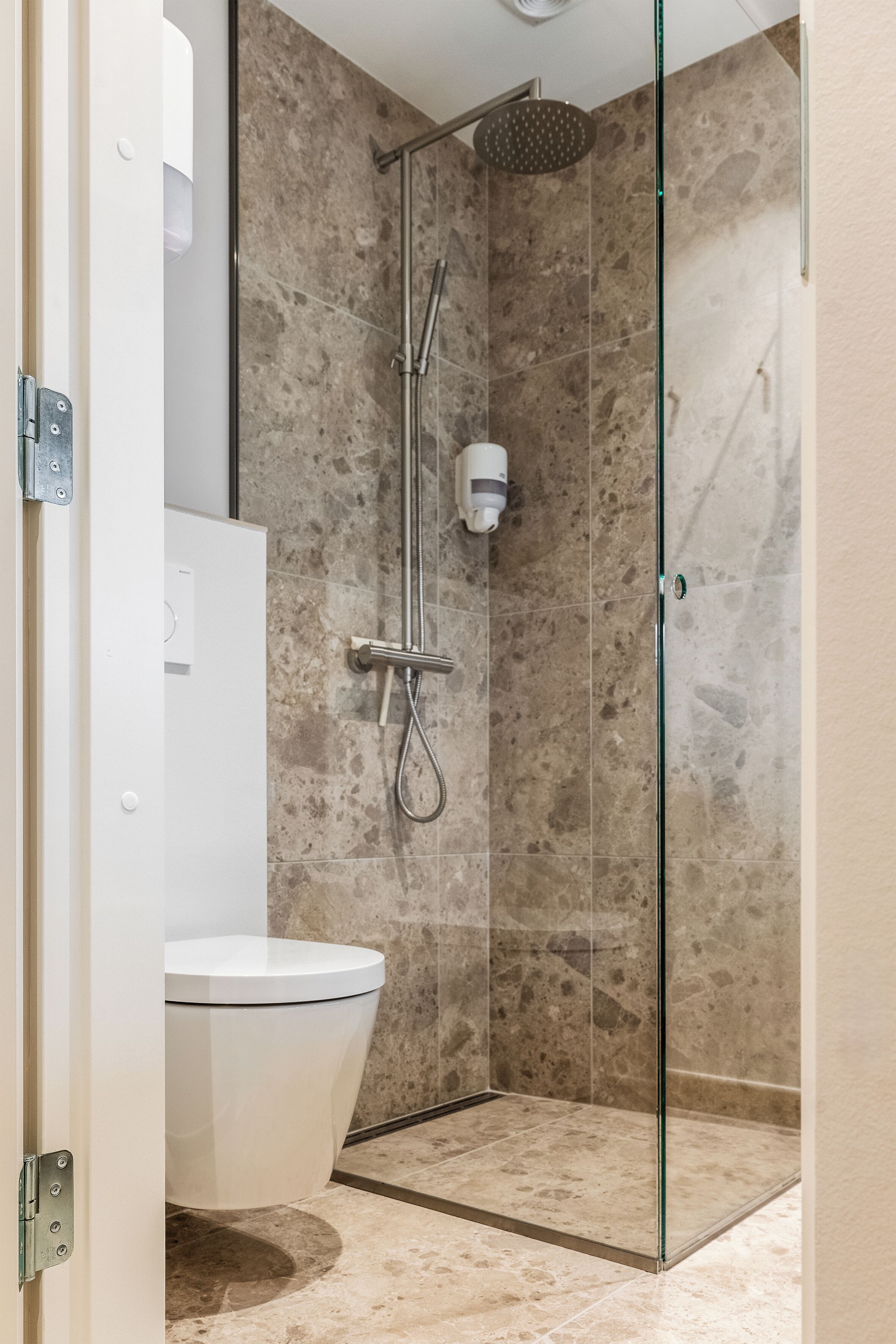 Un bagno moderno con cabina doccia in vetro, un WC bianco e pavimento in marmo.