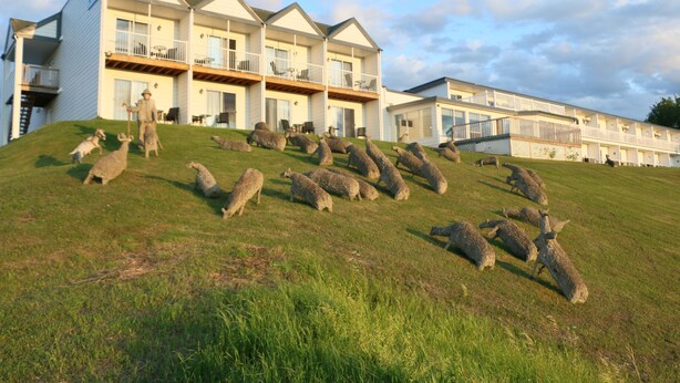 A building with multiple balconies and a grassy slope. - Mon Joli Motel (Sainte-Flavie)