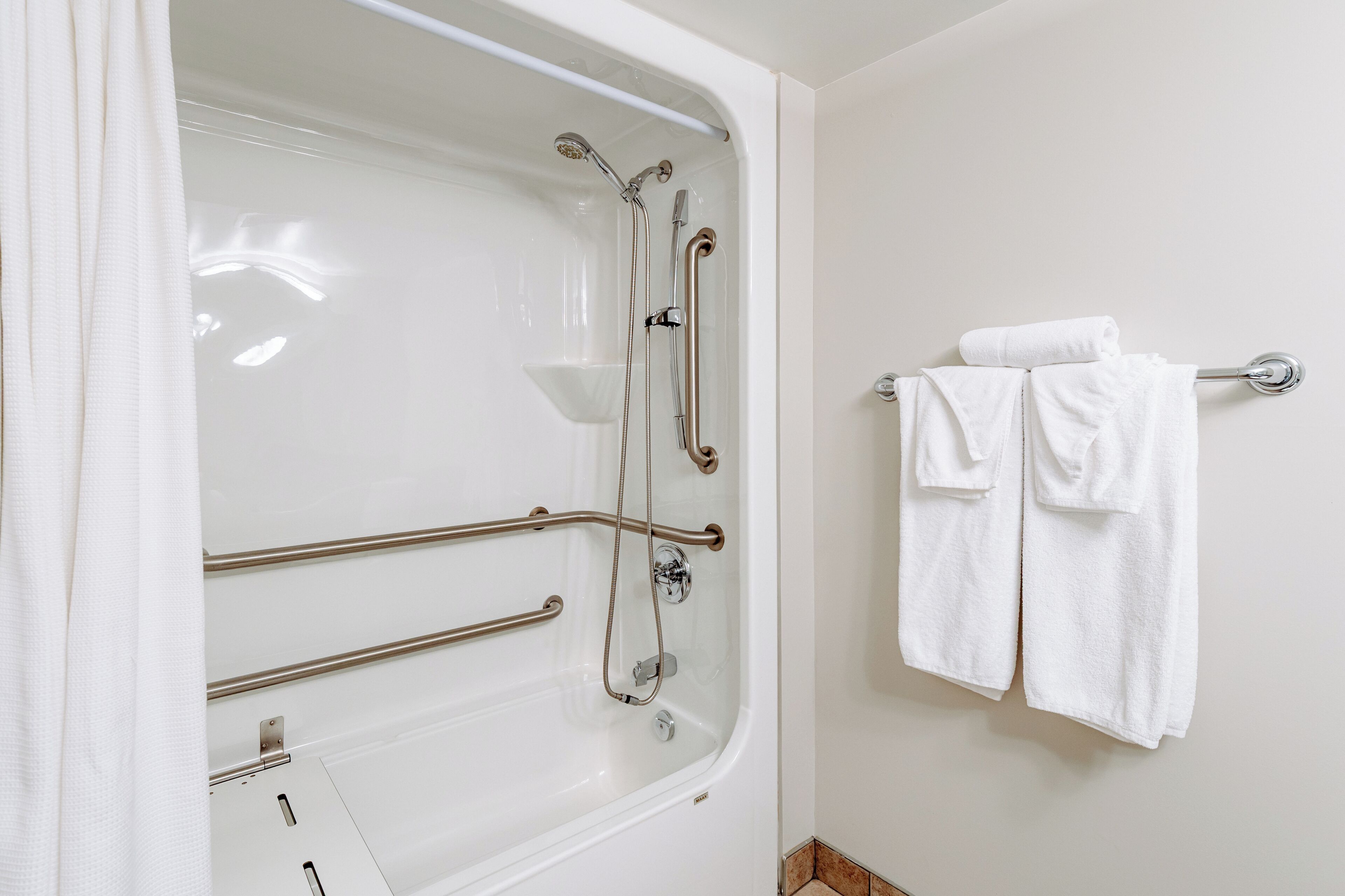 A bathroom with a bathtub, grab bars, and a towel rack.