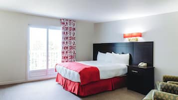 Una habitación de hotel con una cama, una mesita de noche con teléfono, una silla y una ventana con cortinas.