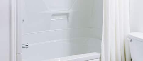 Un baño con bañera, inodoro y piso de baldosas marrones.