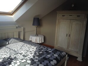 A bedroom with a skylight, a bed with a polka dot bedspread, a small round table with a lamp, and a wooden wardrobe. - Vertes Feuilles (Frasnes-Lez-Anvaing)