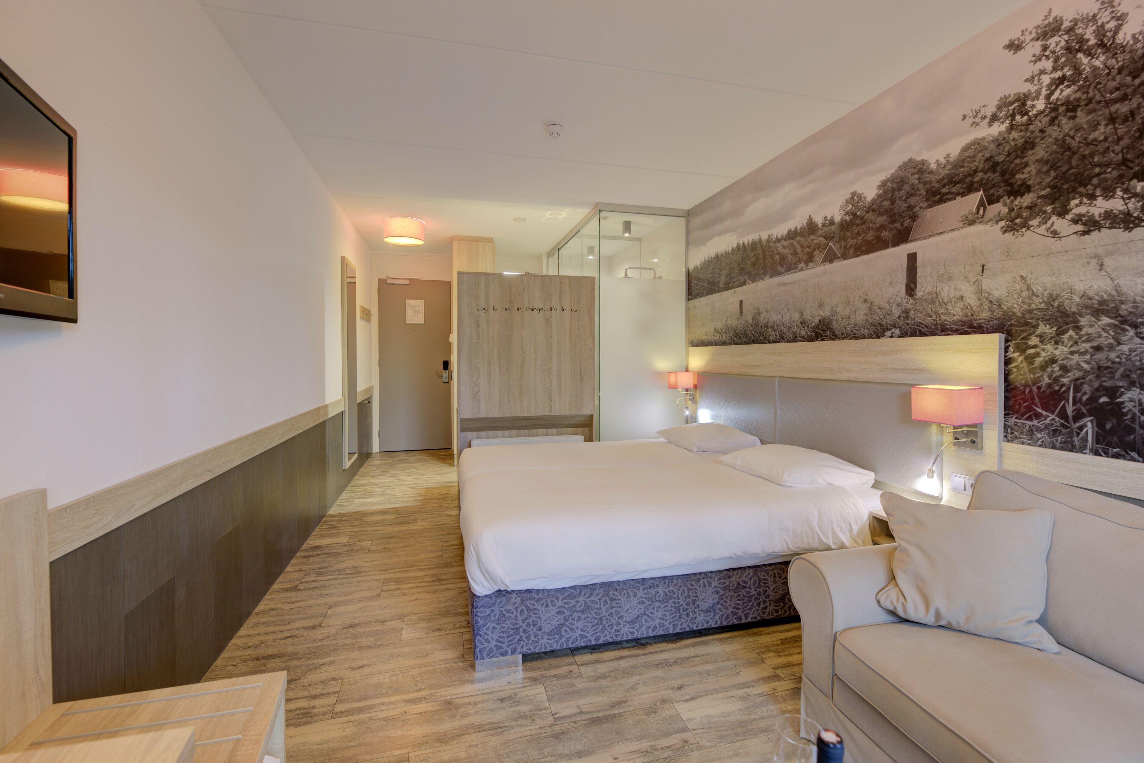 Ein Hotelzimmer mit einem großen Bett, einer Couch, einem Spiegel und einem Bild an der Wand.