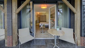 A hotel entrance with a wooden facade, a glass door, and a small table with chairs outside. - Hotel Erve Hulsbeek (Oldenzaal)