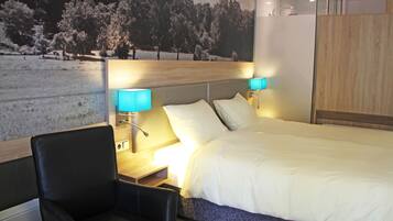A modern hotel room with a large bed, two bedside lamps, a wooden headboard, a black leather chair, and a scenic wall mural.