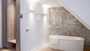 Une salle de bain moderne avec une baignoire sur pieds, un placard en bois et un mur à texture.