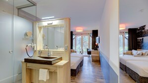 A modern hotel room with a wooden vanity, a large mirror, a sink, and a bed with a view of the outdoors. - Hotel Erve Hulsbeek (Oldenzaal)