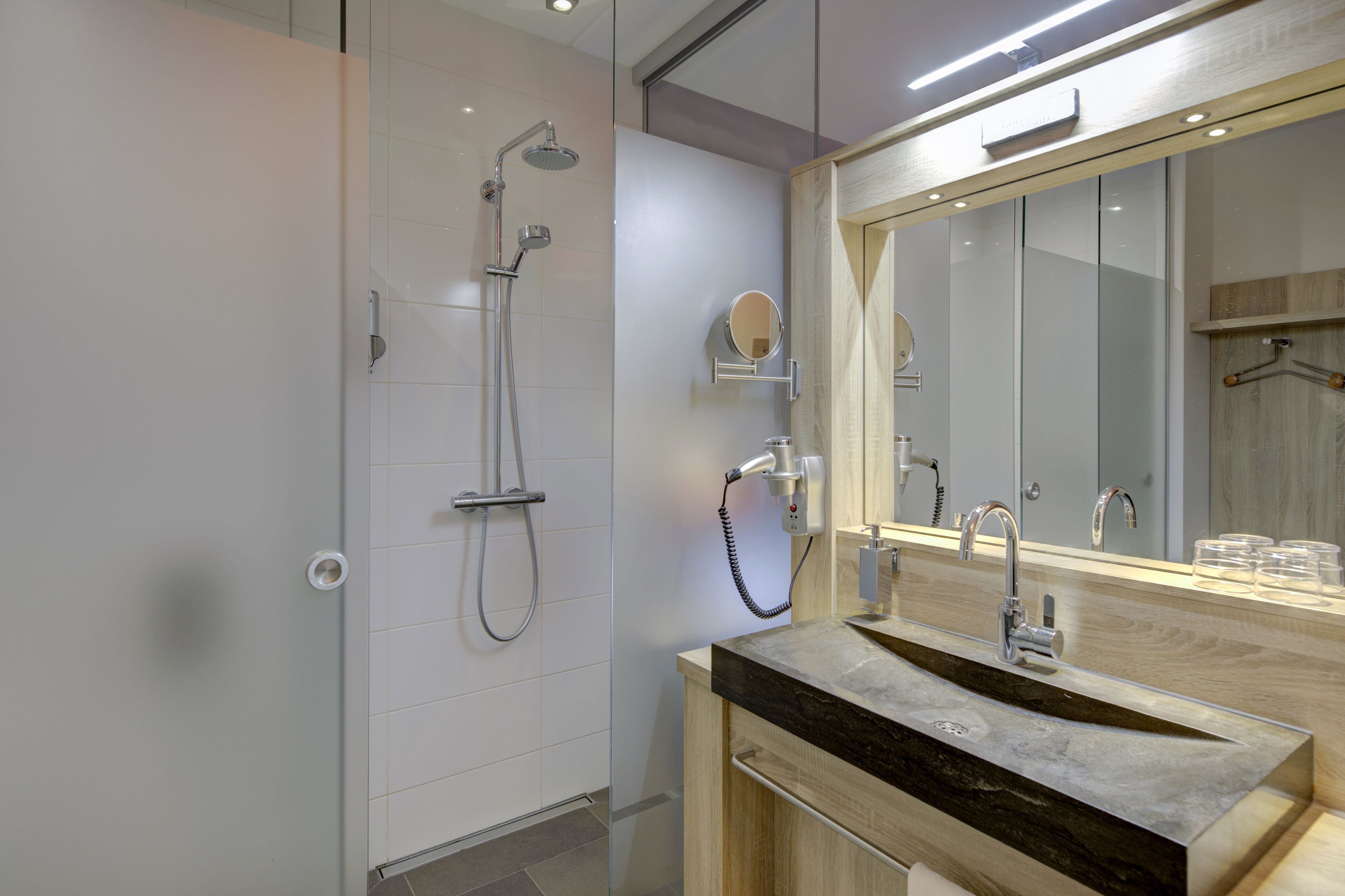 A modern bathroom with a glass shower enclosure, a vanity with a marble countertop, and a large mirror.