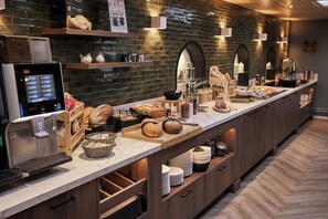 A buffet setup with a coffee machine, bread, and various food items.