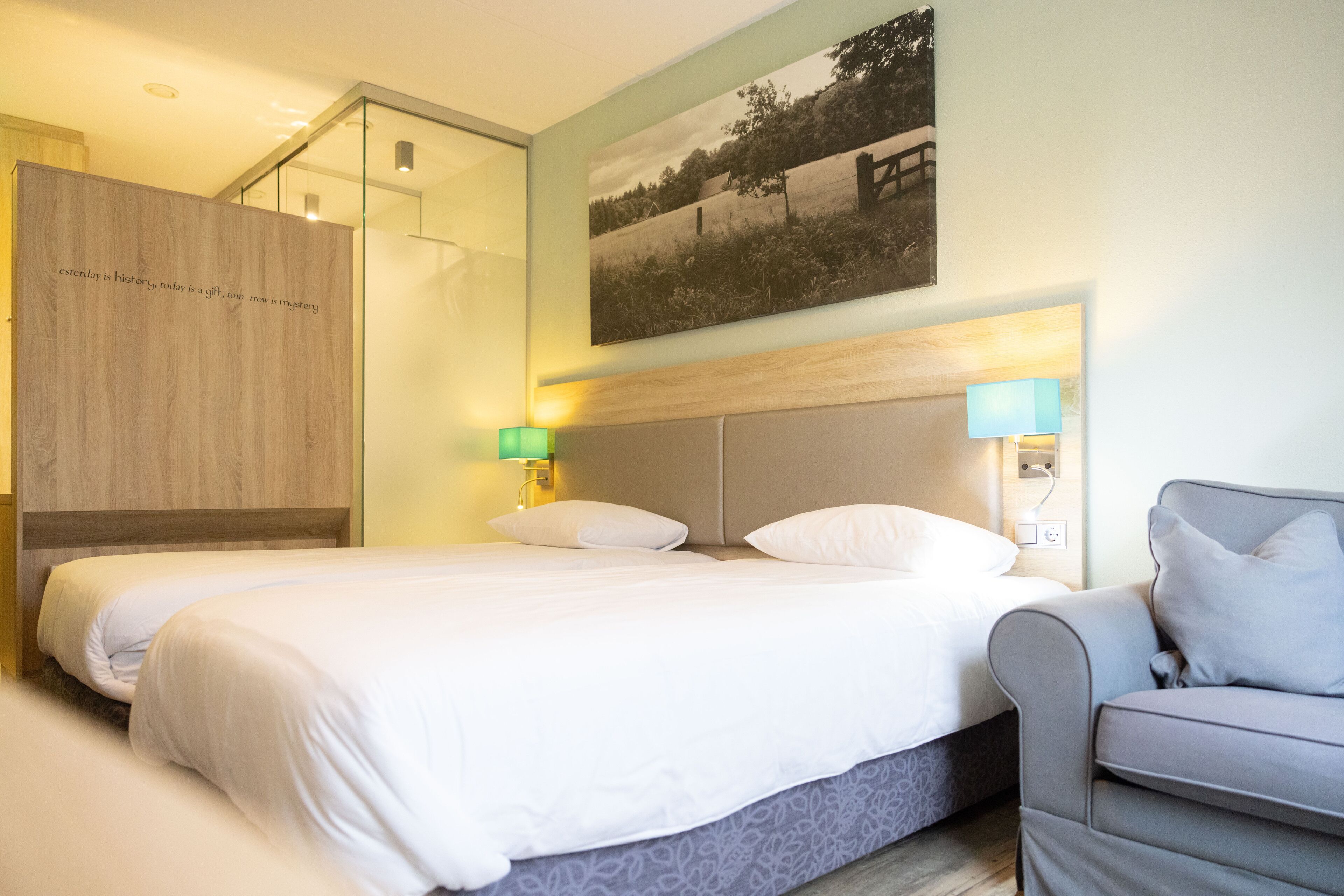 Et moderne hotelværelse med en stor seng, en grå sofa og et billede hængt på væggen.