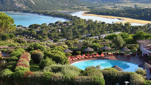 A resort with a swimming pool surrounded by lush greenery and red lounge chairs. - Hôtel Alivi di Santa Giulia (Porto-Vecchio)