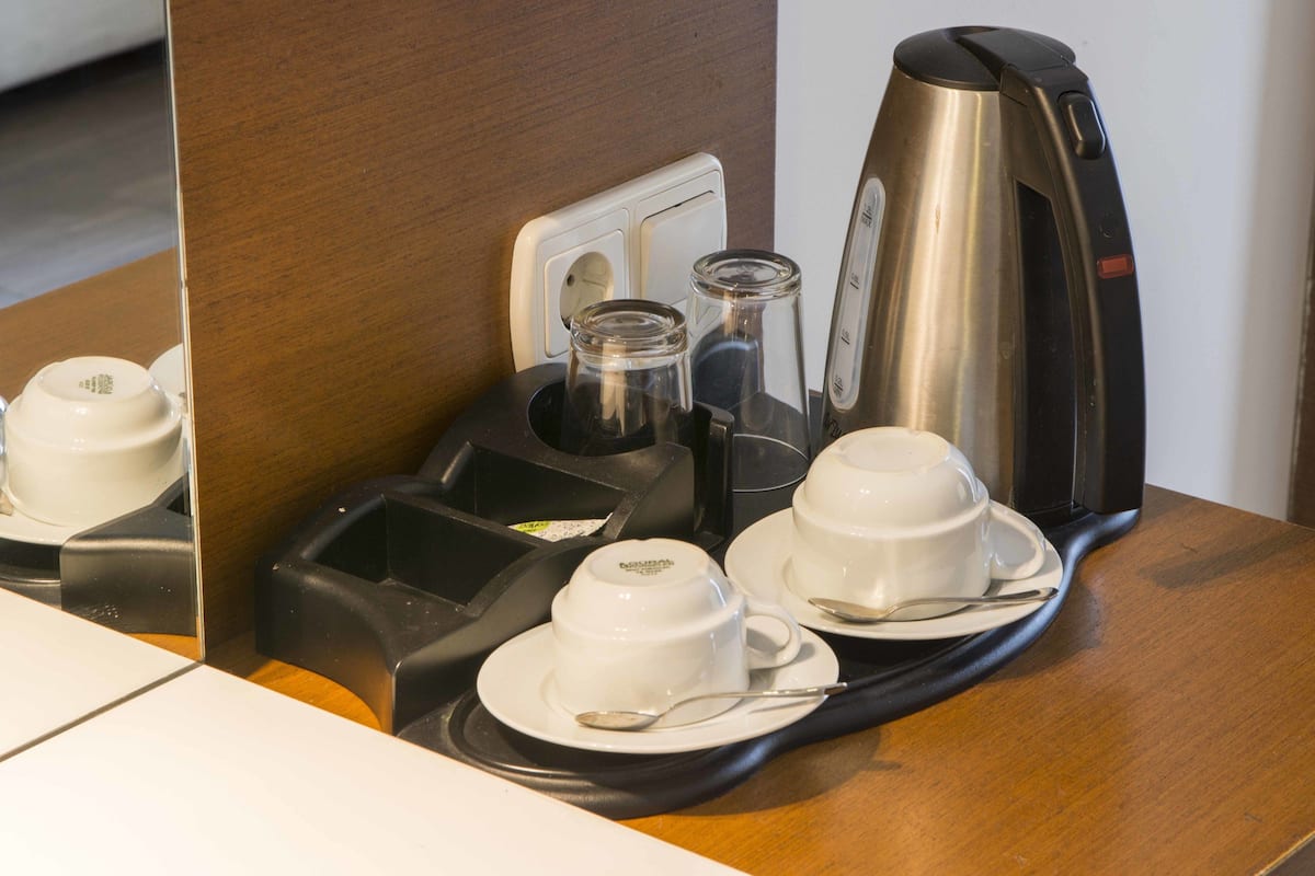 Una estación de café con cafetera, tazas y bandeja.