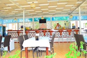 Un restaurant doté d’un bar, de tables, de chaises et d’un plafond décoratif.