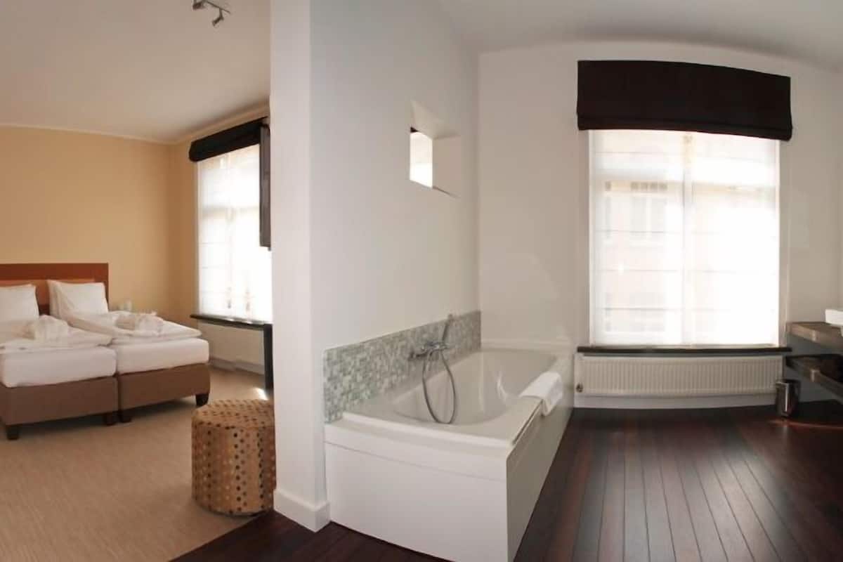 Una habitación de hotel con cama, bañera y ventana.