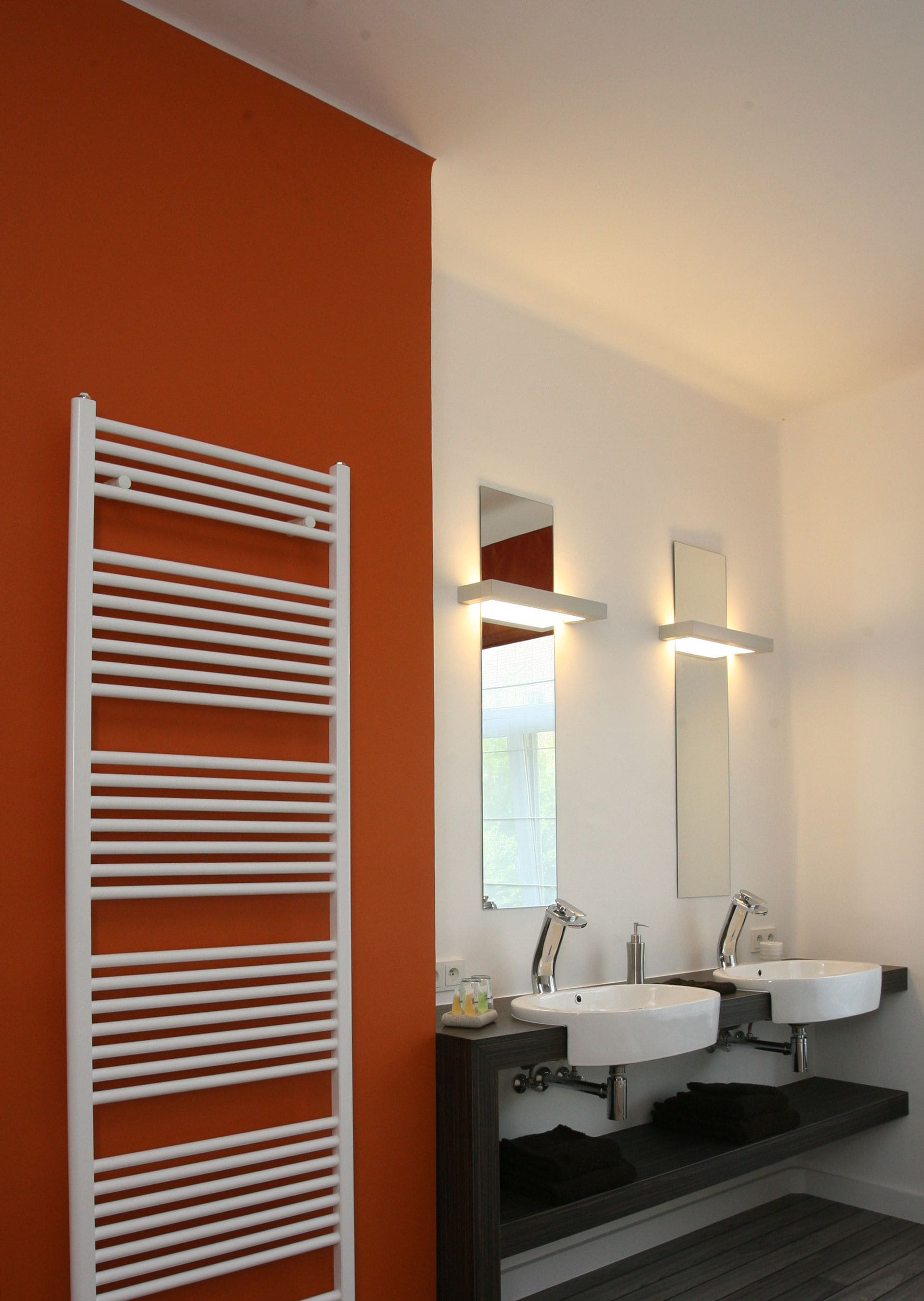 A modern bathroom with two sinks, a large mirror, and a towel rack.