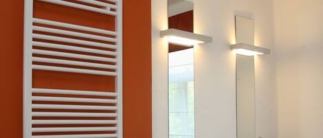 A modern bathroom with two sinks, a large mirror, and a towel rack.