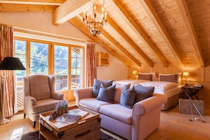 Una habitación acogedora con cama, sofá, silla, mesa y ventana con cortinas.
