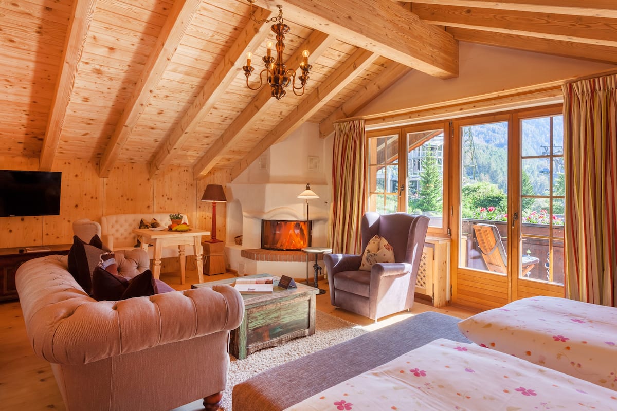 Um interior acolhedor em madeira, com sofá, poltrona e lareira.