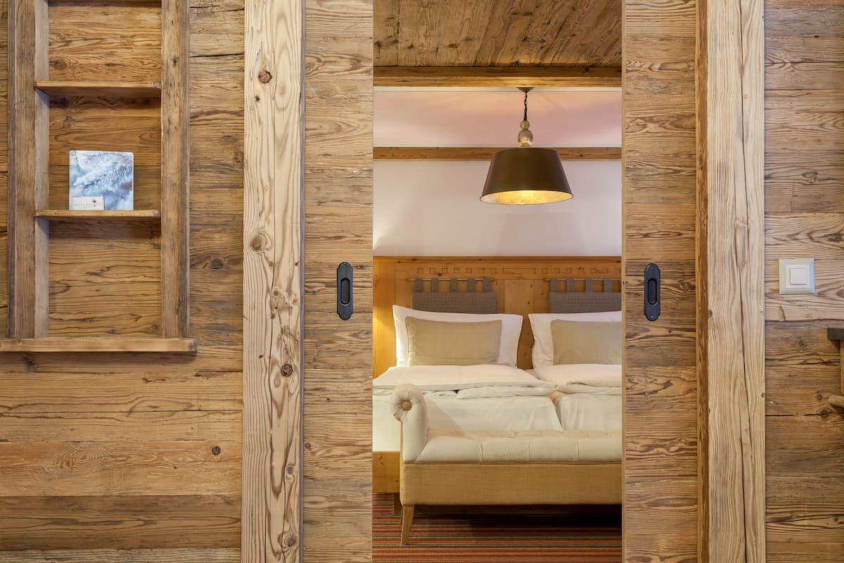 Interior de madeira com uma cama, uma luminária pendente e uma prateleira com um quadro.