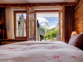 Un dormitorio con una cama grande, paredes de madera y vistas a la montaña.