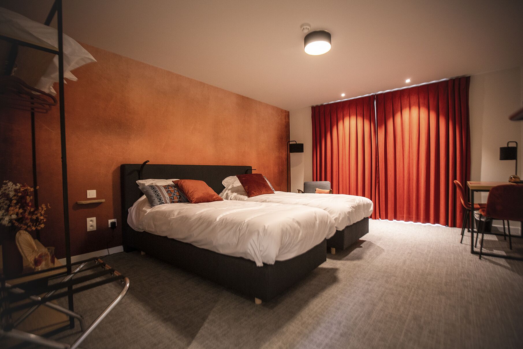 A hotel room with a large bed, a desk, and a chair.