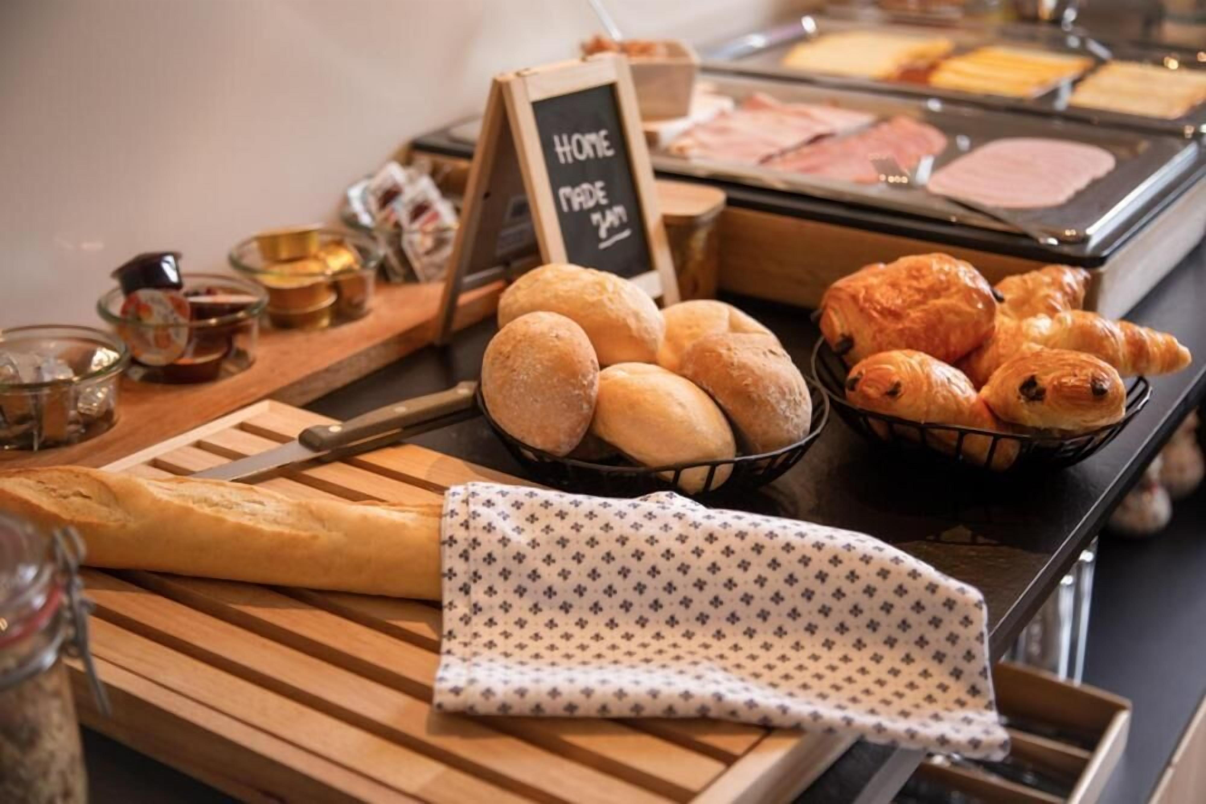 A breakfast buffet with bread, croissants, and a sign indicating homemade items.