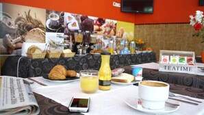 A breakfast setup with croissants, juice, and coffee on a table, with a 'TEATIME' sign in the background. - Hostal Isabel II (Figueres)
