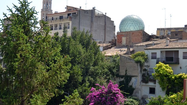 A building with a dome and a bell tower, surrounded by trees and buildings. - Hostal Isabel II (Figueres)