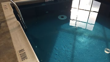 Uma piscina com um aviso de 'Não Mergulhar', uma etiqueta 'Não Mergulhar' na borda da piscina e um aviso de 'Profundidade' indicando a profundidade.