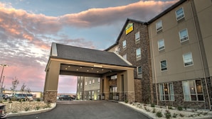 A hotel with a covered entrance, stone facade, and multiple windows. - Western Star All Suites Signature Hotel (Estevan)