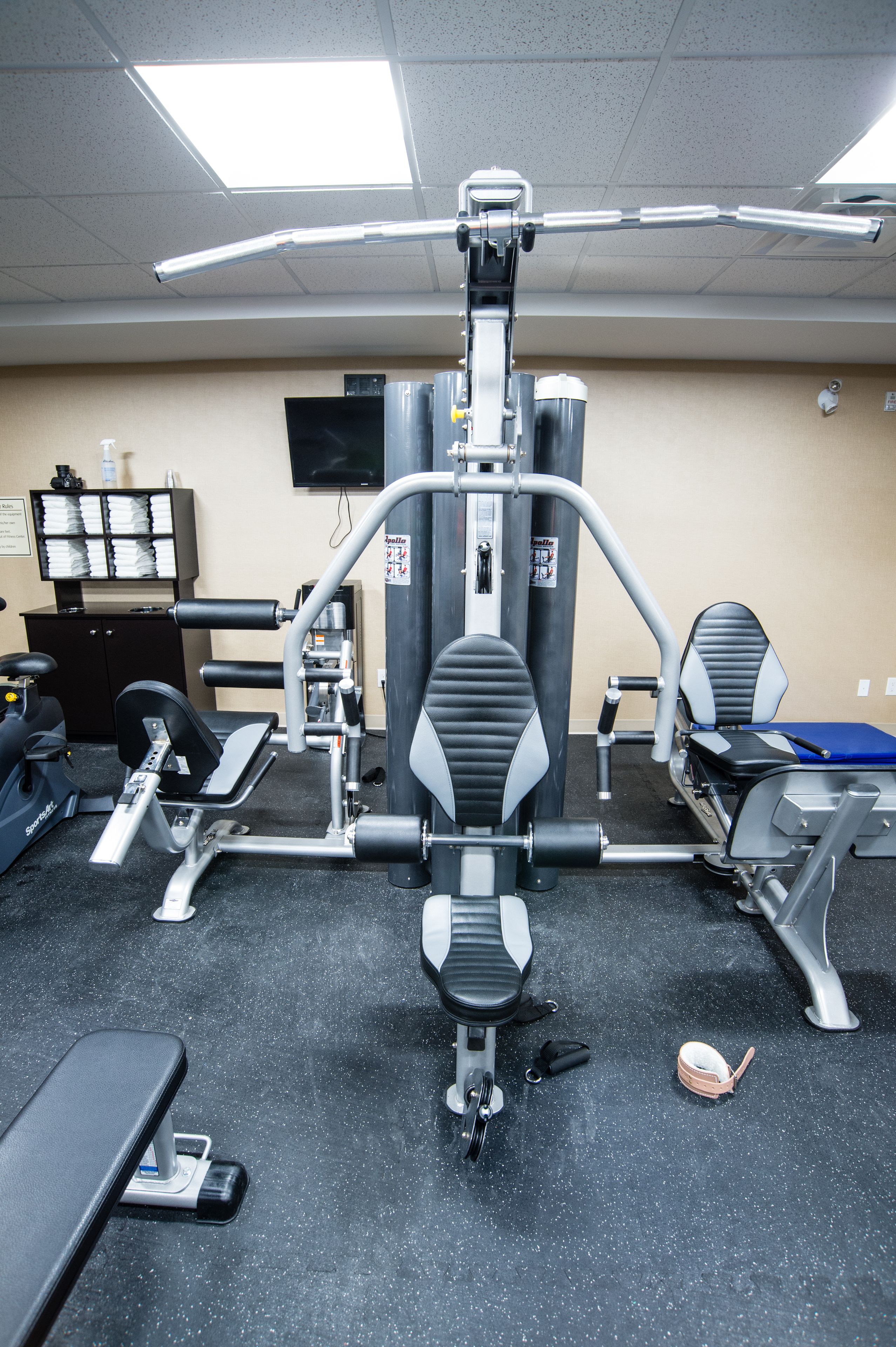 Ett gym med träningsutrustning, en tv och ett arkivskåp.