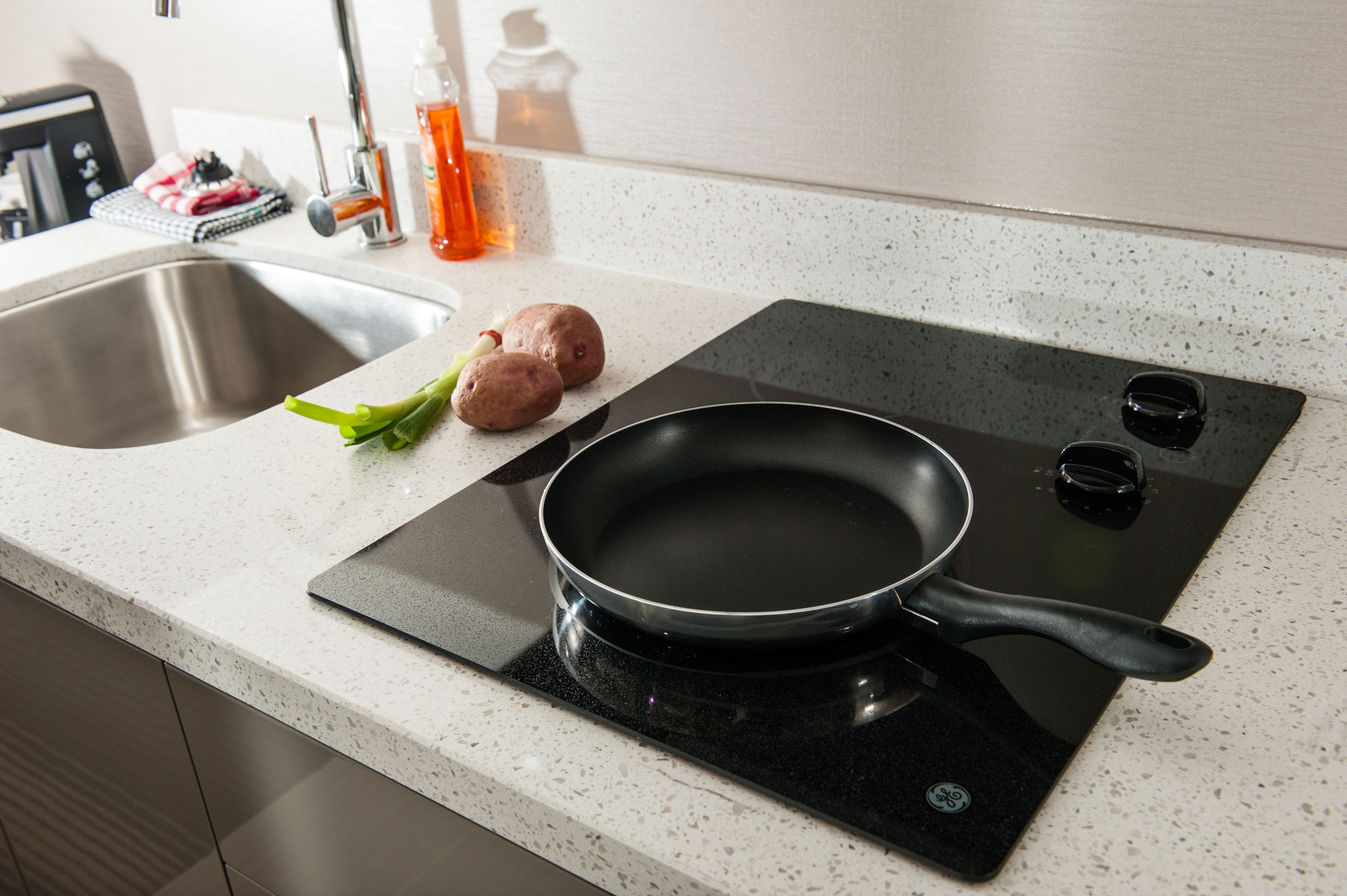 A kitchen with a stovetop, sink, and countertop.