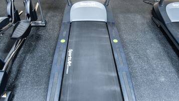 A treadmill in a gym with a control panel and a foot pedal.