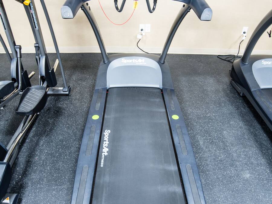 A treadmill in a gym with a control panel and a foot pedal.