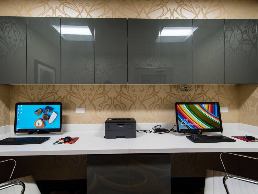 A desk with two monitors, a printer, and a keyboard.