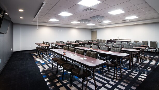 A conference room with multiple tables and chairs, a patterned carpet, and ceiling lights.