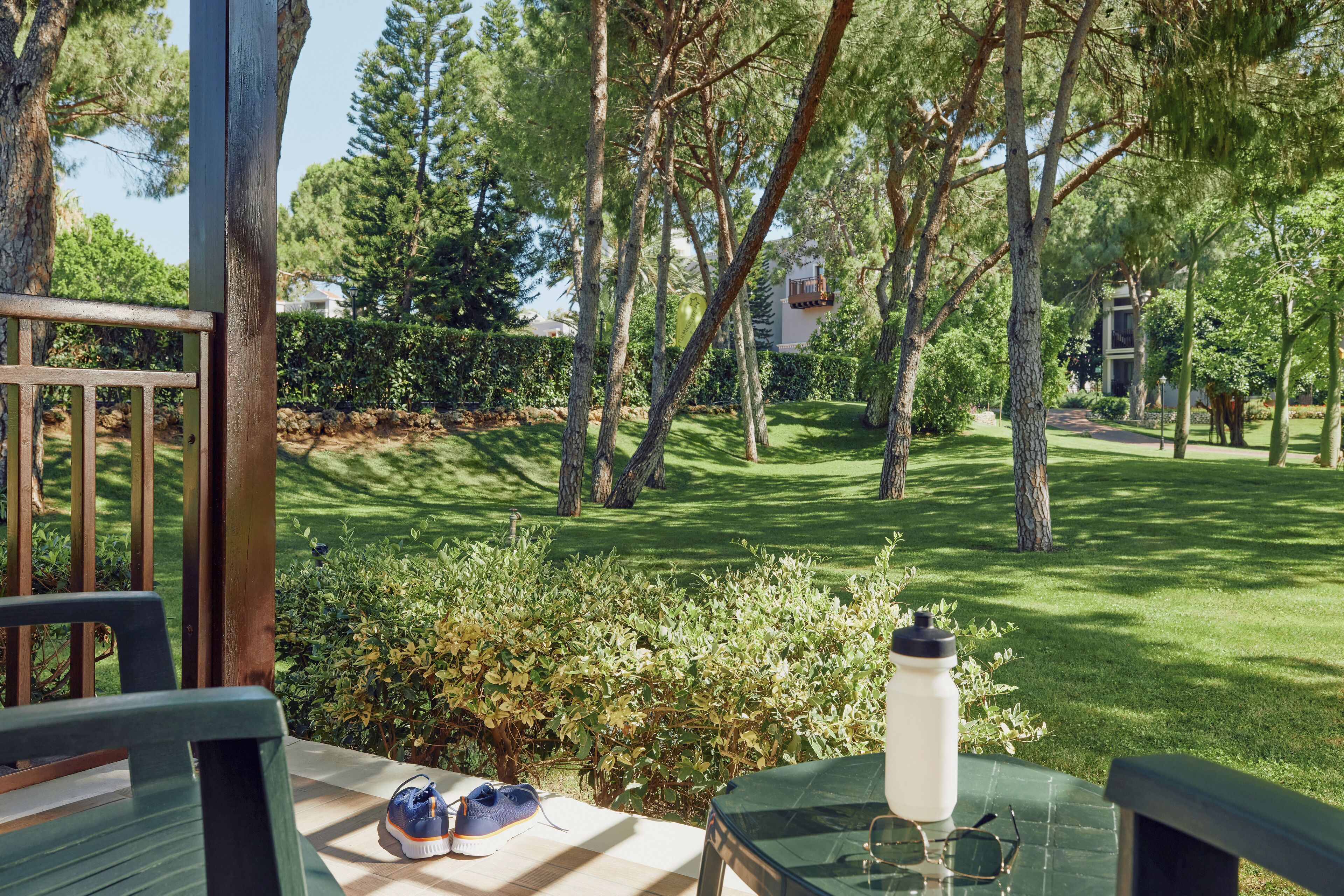 An outdoor seating area with a table, chairs, a water bottle, and a pair of shoes.