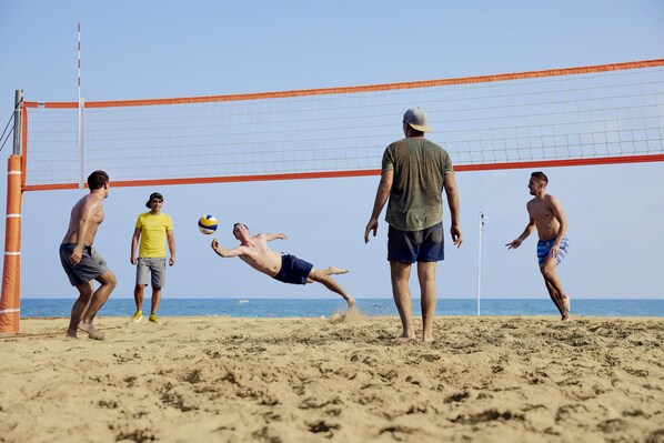 Un partido de voleibol de playa con jugadores vestidos con ropa casual de playa.