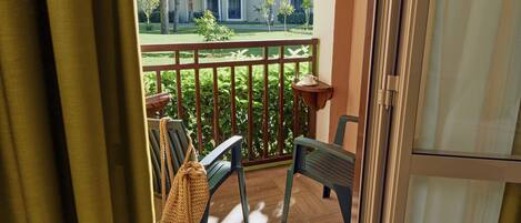 A balcony with a view of a residential area, a wooden bench, and a woven bag.