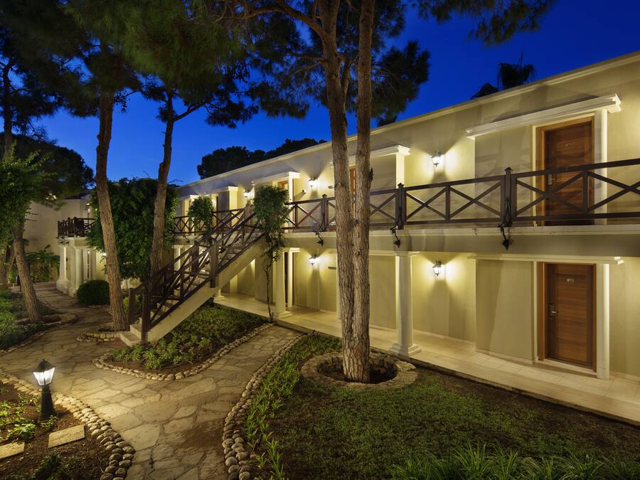Un hotel de varios pisos con un área exterior cubierta, un camino de piedra y una escalera de madera.