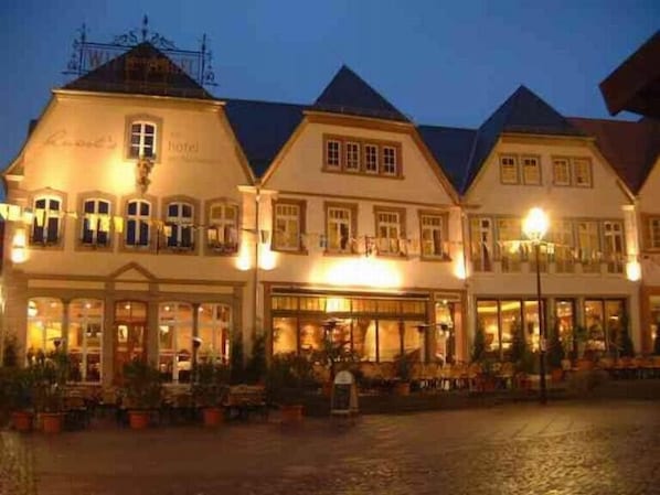 A traditional European hotel with multiple stories, large windows, and a courtyard with outdoor seating. - Angels - das Hotel am Fruchtmarkt (Sankt Wendel)