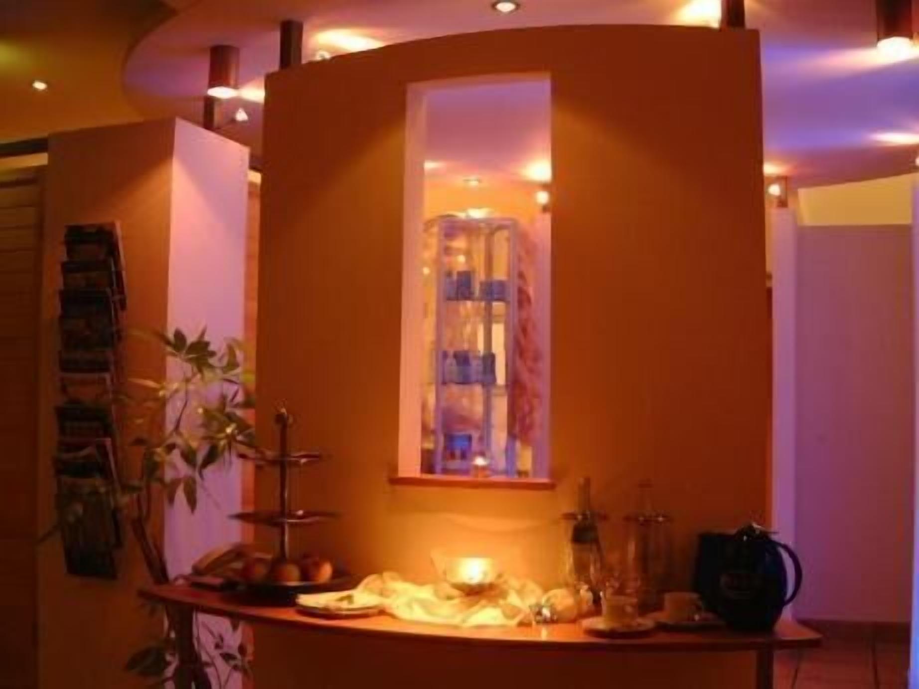 A room with a curved wall, a window with curtains, a small table with a lamp, and a plant.