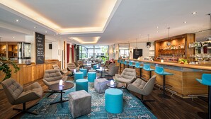 Un espace de détente moderne, doté de sièges confortables, d’un bar et offrant une vue sur l’extérieur.