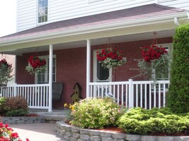 A house with a covered porch, red brick walls, and hanging flower baskets.