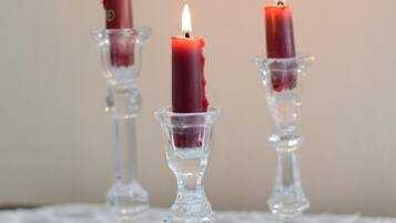 Three lit candles in glass holders on a lace tablecloth.