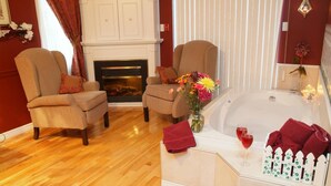 Una habitación con dos sillones, una chimenea, una bañera y un florero con flores.